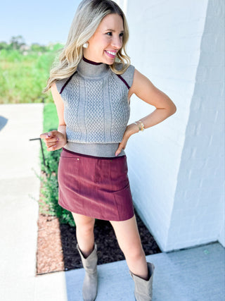 Woman wearing a gray sleeveless top and maroon skirt outdoors.